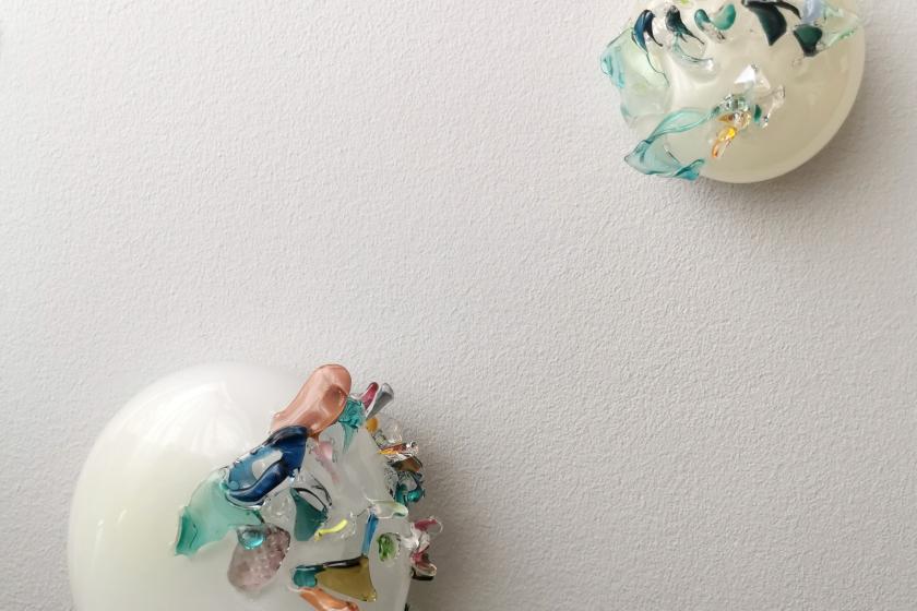 two glass sculptures hanging on wall